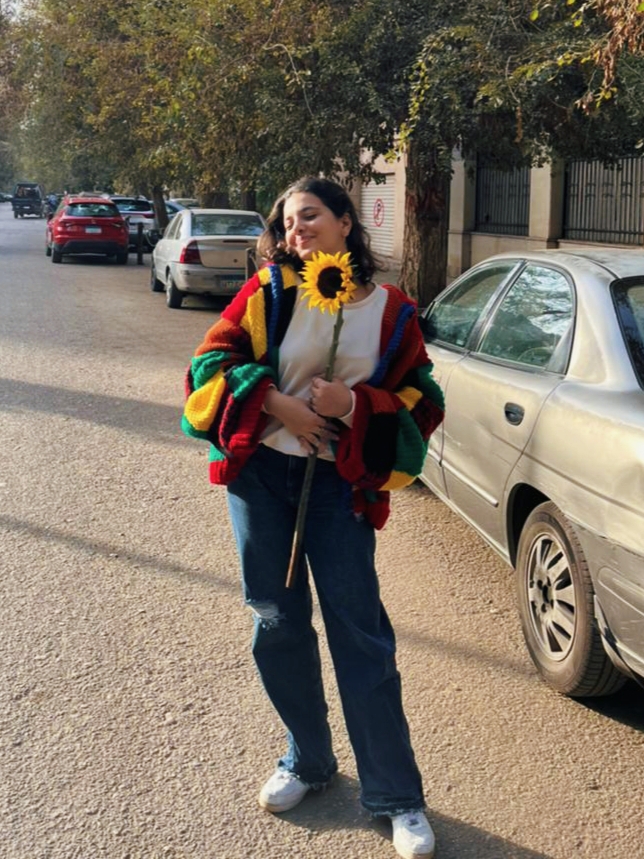 Farida Abu Sulieman holding a sun flower in the middle of the street