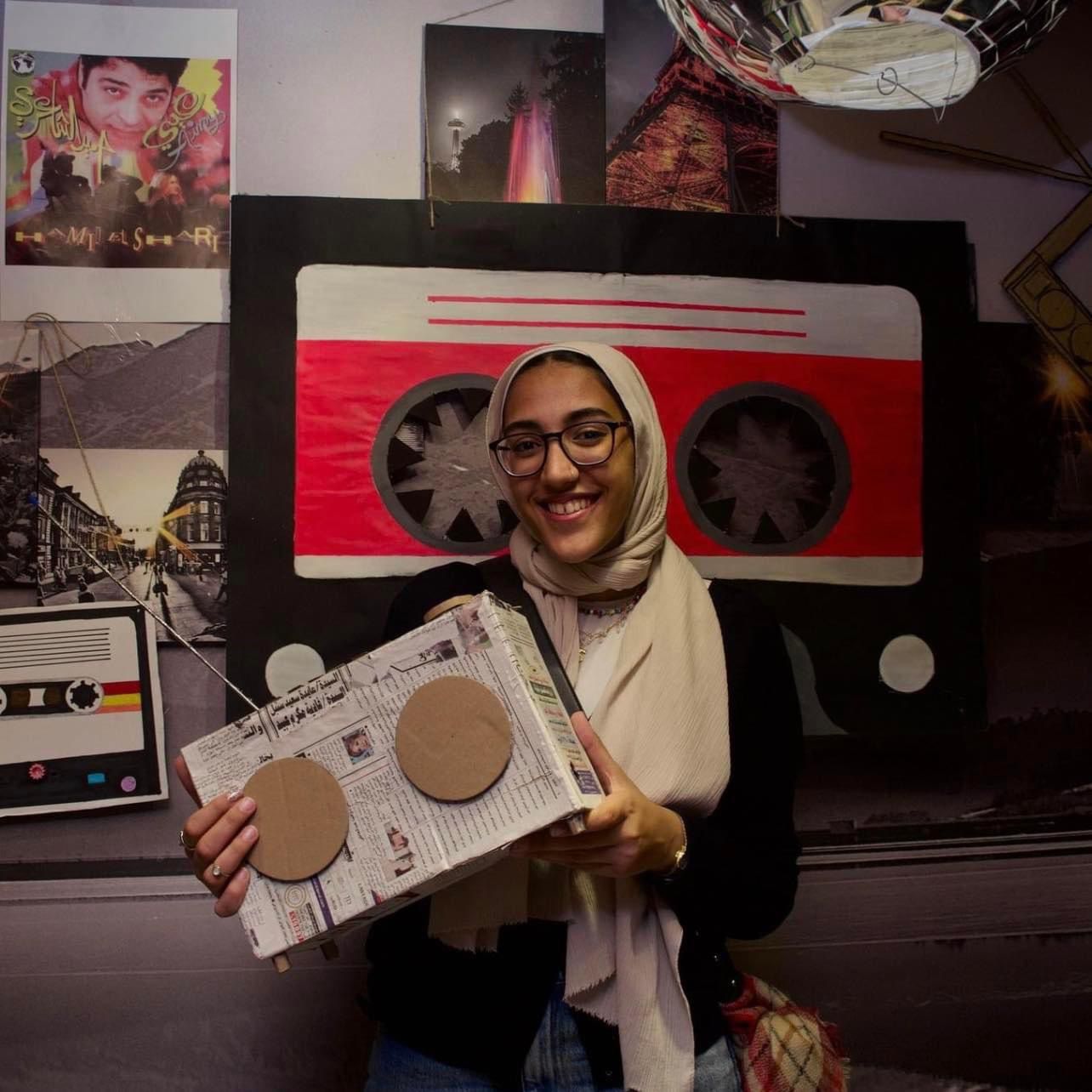 Rawan Saad holding her science far project at a painting area